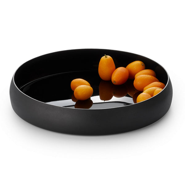 Black circular tray with side walls used for decoration with small faux apricots inside