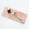 Small pink marble with perfume spray and jade roller on top